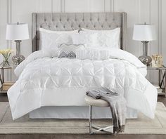 a bed with white comforter and pillows in a bedroom next to two nightstands