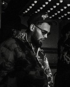 black and white photograph of a man with sunglasses on looking at his cell phone in the dark