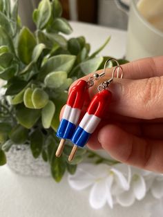 two red, white and blue toothpicks are being held in front of a potted plant