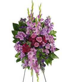 a bouquet of pink and purple flowers in a vase on top of a white stand