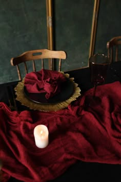 a candle is sitting on a table with a red cloth and two chairs in the background