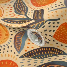 an orange and blue wallpaper with colorful leaves on it's surface, including a roll of tape