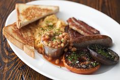 a white plate topped with toast, beans and sausage