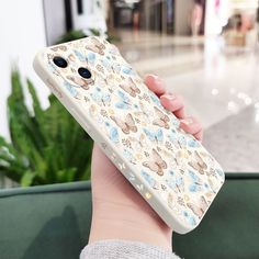 a person holding up a phone case with animals on it in front of a plant