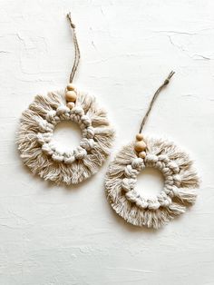 pair of earrings with wooden beads hanging from string on white wall background, top view