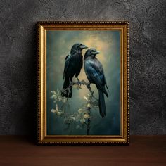 two black birds sitting on top of a tree branch in front of a framed painting