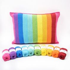 a crocheted pillow and several skeins of yarn sitting next to each other