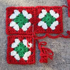 a crocheted square with white and green flowers on it sitting on the ground