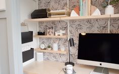 the computer desk has two monitors on it and is next to a book shelf with books