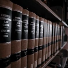 rows of black and brown books on shelves in a library