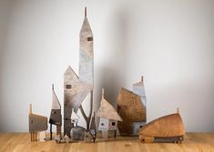 a wooden table topped with lots of cut out houses next to each other on top of a hard wood floor