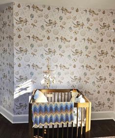 a baby's room with a crib and wallpaper