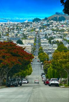 a street with cars parked on both sides and trees lining the road in front of it