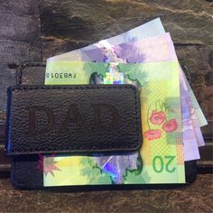 a wallet with the word dad written on it sitting next to some money and other bank notes