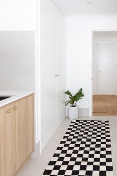 a black and white checkered rug is in the middle of a room with wood cabinets