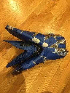 an upside down blue fighter jet sitting on top of a wooden floor next to a bag