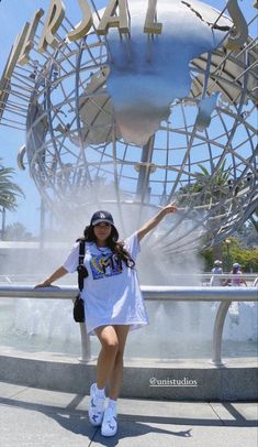 a woman standing in front of a fountain with her arms out and the word peace painted on it