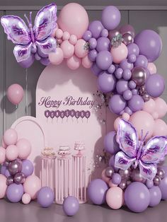 a birthday party with balloons and butterflies on the wall, including a cake table for two