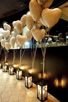 many white heart shaped balloons are hanging from the ceiling in front of some candles and lanterns