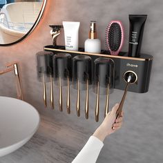 a person is holding a hairbrush and comb in front of a sink with other items on it