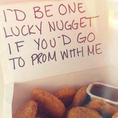 a box filled with fried doughnuts next to a sign that says i'd be one lucky nugget if you'd go to prom with me