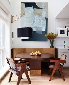 a dining room table with two chairs and a painting on the wall