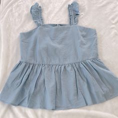 This Sky Blue Cotton Bleu Top Is Light And Airy, With Delicate Ruffles On The Straps. The Bodice Is More Fitted And Then It Flares At The Bottom For A Really Flattering Fit. The Back Has A Dainty Keyhole And Tie. And Cotton Bleu Is A “Pre-Shrunk” Brand, So You Don’t Have To Worry About This Shrinking In The Wash! It Measures Approximately 21” From Underarm To Underarm And About 28” In Length, And The Material Is 75% Rayon, 25% Polyester. C2 Light Blue Ruffled Blouse For Beach, Casual Ruffled Peplum Top For Beach, Light Blue Ruffled Tops For Brunch, Blue Ruffle Hem Top For Day Out, Sleeveless Light Blue Tops For Brunch, Light Blue Sleeveless Top For Brunch, Blue Tops With Ruffled Straps, Cheap Blue Ruffled Top, Blue Ruffle Hem Top For Beach