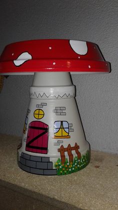 a red and white mushroom shaped object sitting on top of a wooden table next to a wall