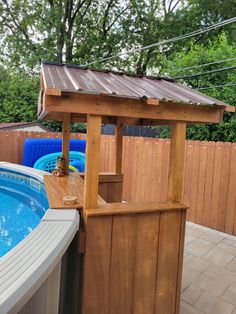 a wooden gazebo next to a swimming pool in a back yard with a hot tub