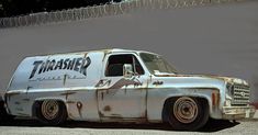 an old white truck parked in front of a wall with graffiti on it's side