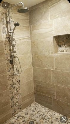 a walk in shower sitting next to a tiled wall and floor with pebbles on it