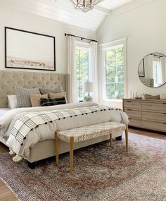 a bedroom with a large bed, dresser and mirror in it's center area