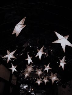 several white stars hanging from the ceiling in a dark room with string lights on it