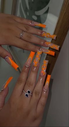 777 Orange Acrylic Nails Prom, Long Nails Coffin Summer, Orange Medium Acrylic Nails, Orange Nail Styles, Long Square Acrylic Nails Orange, Orange Nails With Initial, Extravagant Nail Designs, Baddie Birthday Nails Orange, Orange Sets Nails