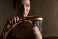 a woman is holding a shower head in front of her face