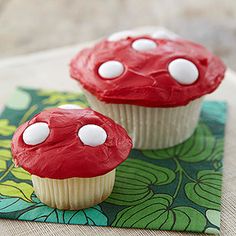 two cupcakes with red frosting and mushrooms on them