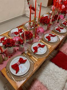 the table is set with red roses and place settings