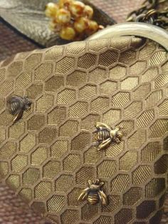 two bees sitting on top of a gold purse