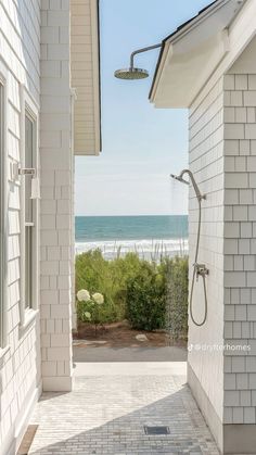 an open door leading to the beach from a white brick house with ocean in background