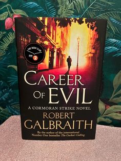 the book cover for career of evil by robert galbrath on a pink table