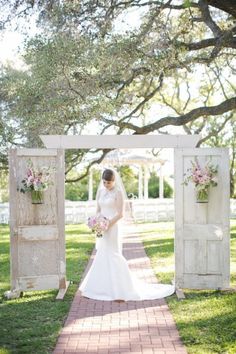 a woman in a wedding dress standing under an archway