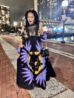 a woman in a black and yellow dress standing on the sidewalk