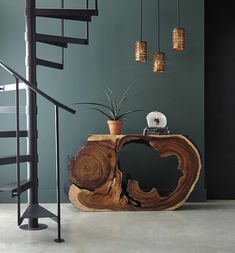 a wooden table sitting next to a spiral stair case in a room with green walls