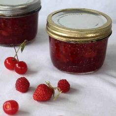 raspberry jam in a jar with fresh berries around it