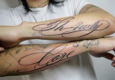 two people with tattoos on their arms holding each other's hands and the word love written in cursive writing