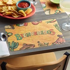 a place mat with the word benvendos on it sits next to chips and salsa