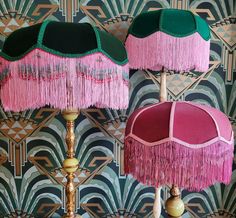 two lamps with pink and green fringes on them against a wallpapered background