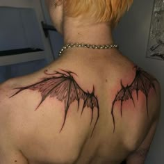 the back of a woman's shoulder with two black wings on her upper arm