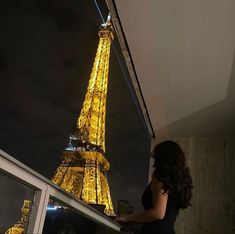 a woman standing in front of the eiffel tower at night