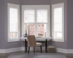 a chair sitting in front of two windows with shutters on each side and a rug on the floor